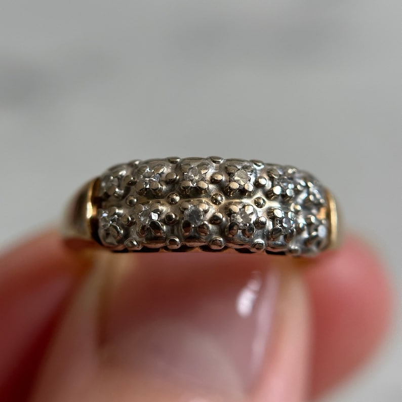 May include: A gold band ring with a double row of small, clear diamonds set in a pave setting.