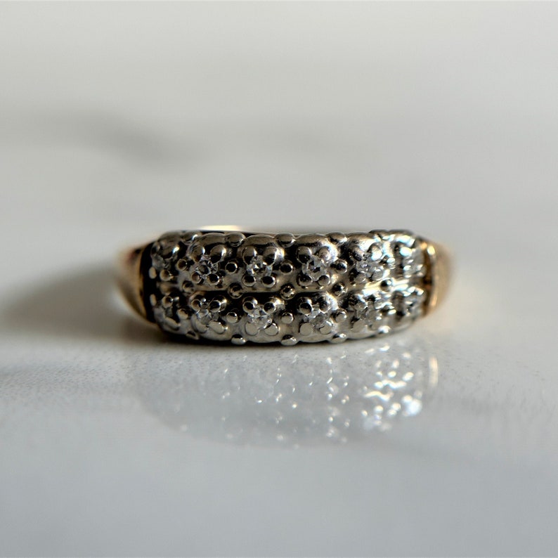 May include: A two-toned gold and silver ring with a band of small diamonds.