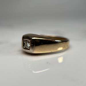 May include: A gold and silver ring with a single diamond set in the center.
