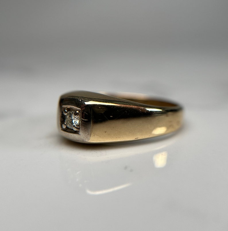 May include: A gold and silver ring with a single diamond set in the center.