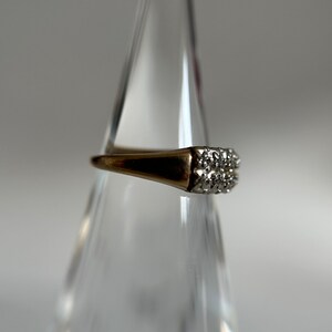 May include: A gold ring with a square-shaped setting of small, clear diamonds.