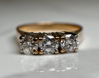 May include: A gold band ring with three round diamonds set in a row.