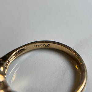 Puede incluir: Primer plano del interior de un anillo de oro con la inscripci&oacute;n "10K OJ" en la banda.