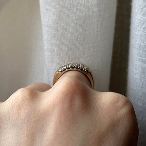May include: A gold band ring with a row of small, clear gemstones.