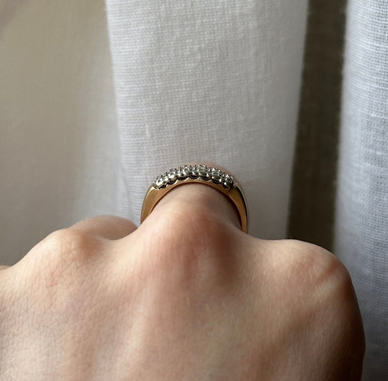 May include: A gold band ring with a row of small, clear gemstones.