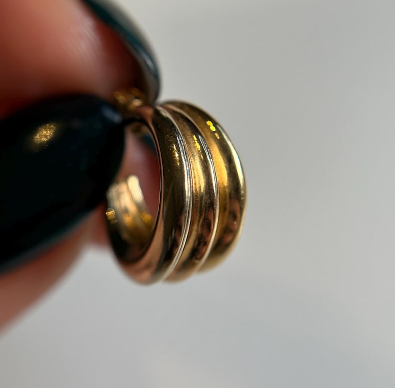 May include: Gold hoop earrings with three layers. The earrings are a classic style and would be a great addition to any jewelry collection.