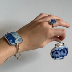 May include: A set of three silver jewellery pieces featuring blue and white porcelain insets. The pieces include a bracelet, a ring, and a pendant. The porcelain insets feature floral and geometric designs.
