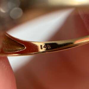 May include: Close-up of the inside of a gold ring with the inscription "14K" on the band.