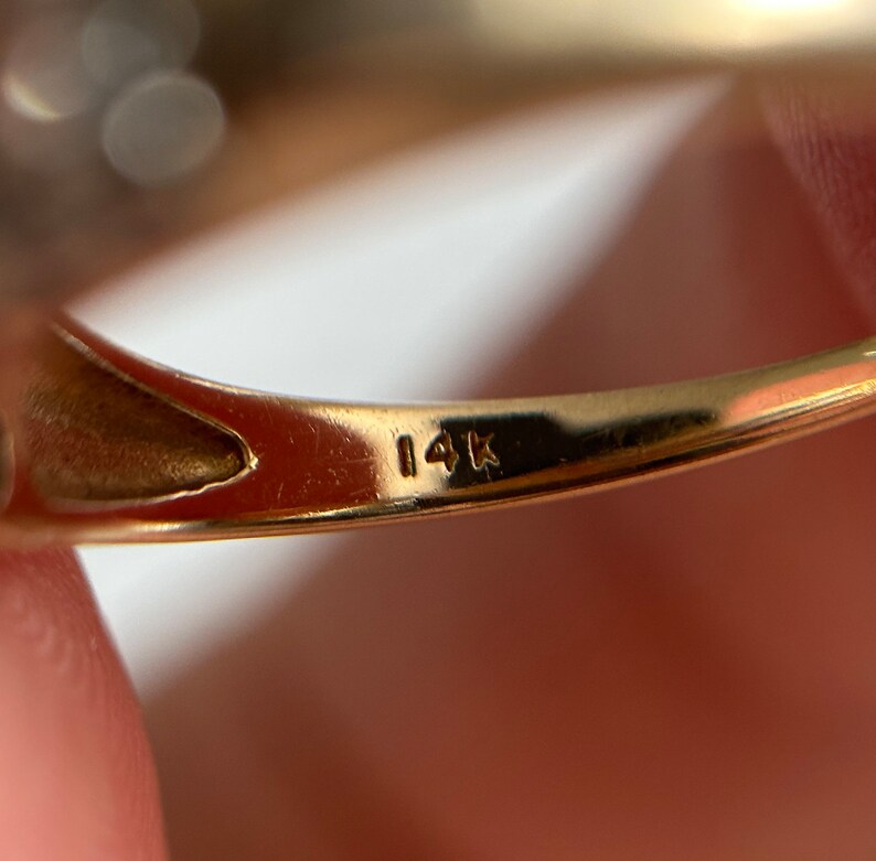 May include: Close-up of the inside of a gold ring with the inscription "14K" on the band.