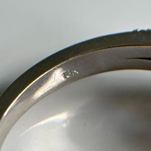 以下が含まれることがあります： 銀の指輪の内側のクローズアップ。バンドに「13K」の刻印があります。