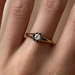 May include: A gold ring with a single round diamond set in a flower-shaped setting.