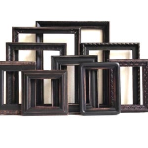 May include: A collection of rectangular picture frames in various sizes, all featuring a dark black finish with subtle copper-toned highlights along the edges. The frames display diverse border textures, including smooth, grooved, and ornate patterns.