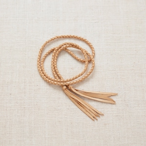 May include: A light brown leather cord with a braided design and tassels at the end.