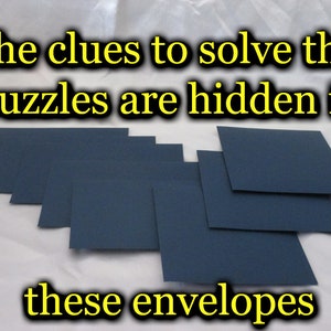 May include: A collection of dark blue envelopes arranged on a white surface. The text at the top reads "The clues to solve the puzzles are hidden in" and the text at the bottom reads "these envelopes".