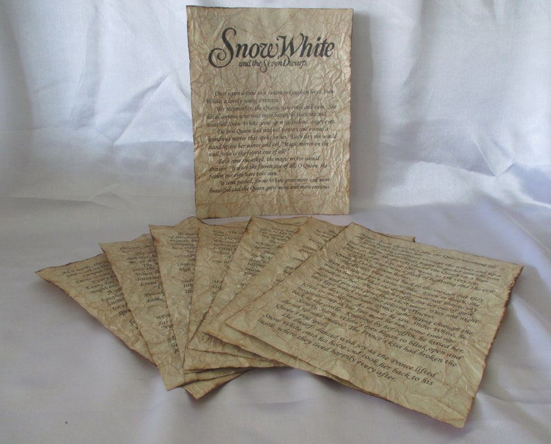 May include: Aged paper pages with text from "Snow White and the Seven Dwarfs". The pages have a vintage, weathered appearance with a sepia tone. The title is displayed on a larger page, with several smaller pages fanned out below.
