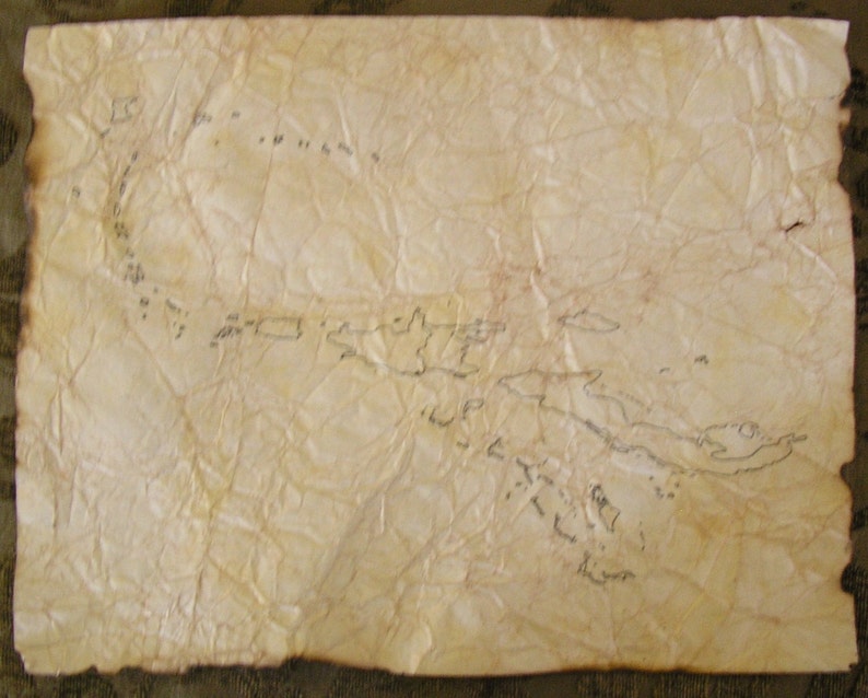 May include: Aged parchment paper with a hand-drawn map. The map features coastlines and islands, with a burnt edge. The paper is heavily creased, giving it an antique appearance. The map is drawn in black ink.