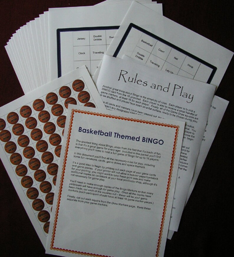 May include: A stack of printed basketball-themed Bingo game materials. Includes rules, game cards, and sheets of basketball-shaped markers. The text on the pages reads "Basketball Themed BINGO" and "Rules and Play".