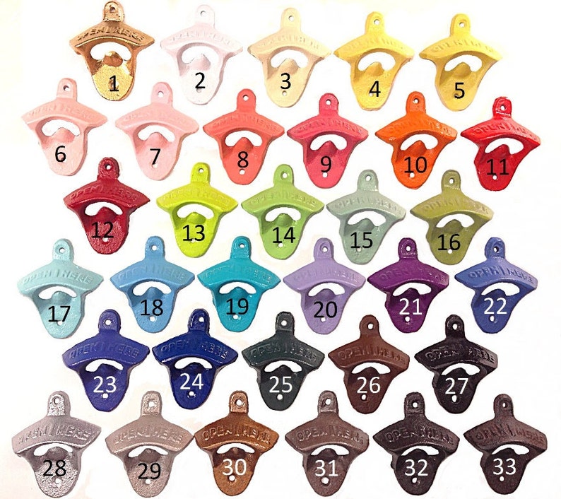 May include: A collection of cast iron bottle openers in various colors, including gold, white, pink, red, green, blue, and brown. Each opener is numbered and features the text "OPEN HERE".