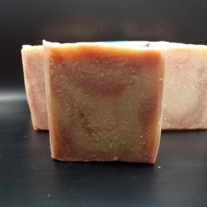 Op de afbeelding: Drie handgemaakte zeepjes met een swirl-patroon in roze en beige tinten.