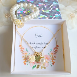 K&ouml;nnte beinhalten: Eine wei&szlig;e Geschenkbox mit einer goldenen Halskette und einem Perlenarmband. Die Box enth&auml;lt eine Karte mit der Aufschrift "Carla, Danke, dass du meine Blumenm&auml;dchen bist".