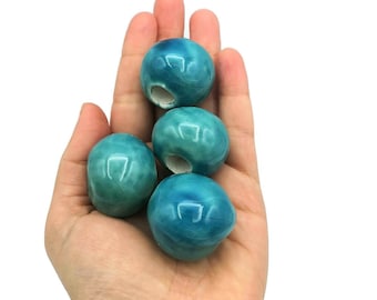 Peut inclure: Quatre perles en céramique bleu sarcelle avec un trou au centre. Les perles sont lisses et brillantes.