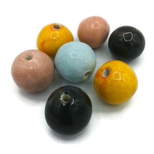 May include: Six ceramic beads in various colors, including yellow, blue, black, and pink. Each bead has a hole through the center.