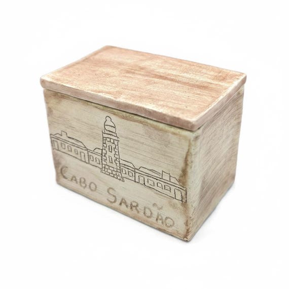 A hand-thrown ceramic box where a tiny sculpted lighthouse acts as the lid handle — functional art that doubles as desk decor.