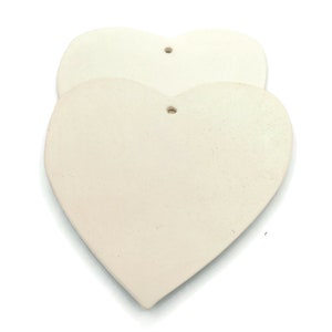 May include: Two off-white, heart-shaped ornaments with a textured surface. Each heart has a small hole at the top for hanging. The hearts are stacked slightly, with one in front of the other, against a white background.