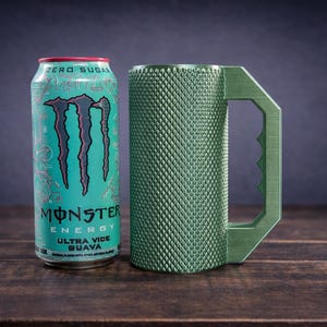 Peut inclure: Une canette de Monster Energy Ultra Vice Guava turquoise avec une marque et du texte noirs &agrave; c&ocirc;t&eacute; d'une tasse cylindrique vert olive dot&eacute;e d'un ext&eacute;rieur textur&eacute; &agrave; motif losange et d'une grande poign&eacute;e angulaire dentel&eacute;e.
