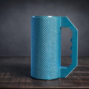 Peut inclure: Un mug cylindrique bleu sarcelle dot&eacute; d'une surface textur&eacute;e &agrave; motif de losanges et d'une poign&eacute;e g&eacute;om&eacute;trique avec trois empreintes digitales distinctes. Le mug pr&eacute;sente une finition mate et un design droit et vertical pour une prise en main.
