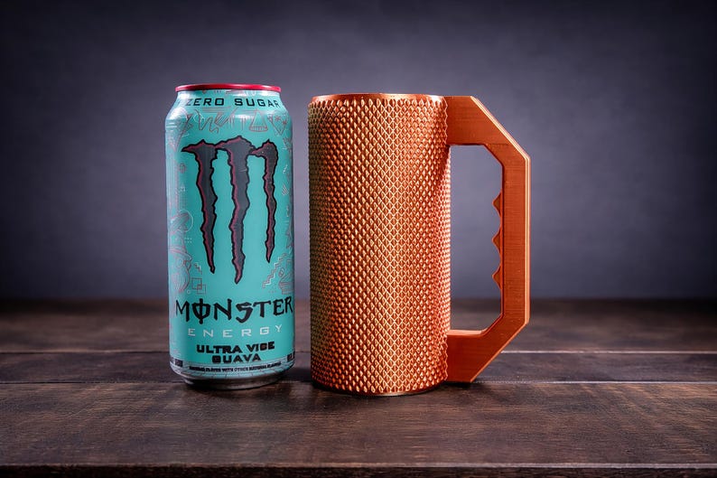 Peut inclure: Une canette de boisson Monster Energy Ultra Vibe Guava bleu clair avec un logo et du texte noirs &agrave; c&ocirc;t&eacute; d'une tasse cylindrique cuivr&eacute;e dot&eacute;e d'une surface textur&eacute;e &agrave; motif losange et d'une grande poign&eacute;e angulaire dentel&eacute;e.