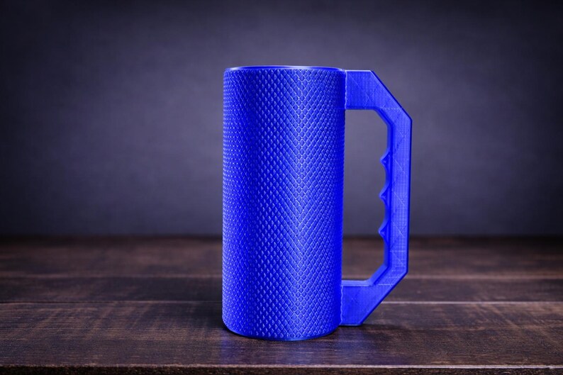 Peut inclure: Un mug cylindrique bleu pr&eacute;sentant une texture molet&eacute;e en losanges sur toute sa surface ext&eacute;rieure. Le mug est dot&eacute; d'une grande poign&eacute;e g&eacute;om&eacute;trique angulaire avec une s&eacute;rie de prises pour les doigts sur le bord int&eacute;rieur.
