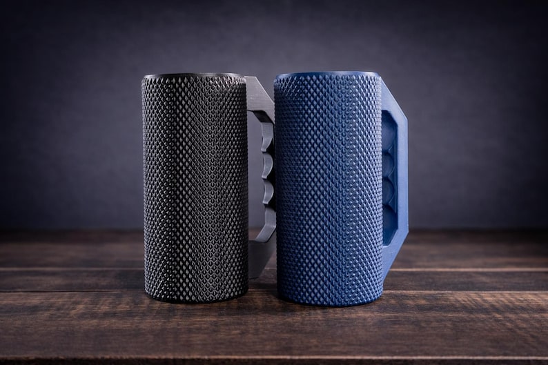 Peut inclure: Deux tasses cylindriques avec une surface ext&eacute;rieure textur&eacute;e &agrave; motif en losange. Une tasse est noir mat et l'autre est bleu mat. Chacune pr&eacute;sente une poign&eacute;e solide et angulaire avec des rainures pour les doigts sur le c&ocirc;t&eacute; int&eacute;rieur.