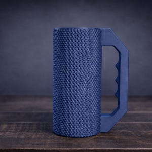 Peut inclure: Une tasse cylindrique bleu marine dot&eacute;e d'une surface ext&eacute;rieure textur&eacute;e &agrave; motif de losanges et d'une poign&eacute;e g&eacute;om&eacute;trique avec des empreintes pour les doigts. Le r&eacute;cipient pr&eacute;sente une base plate et un corps droit avec une finition mate.