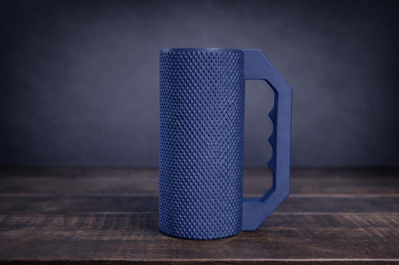 Peut inclure: Une tasse cylindrique bleu marine dot&eacute;e d'une surface ext&eacute;rieure textur&eacute;e &agrave; motif de losanges et d'une poign&eacute;e g&eacute;om&eacute;trique avec des empreintes pour les doigts. Le r&eacute;cipient pr&eacute;sente une base plate et un corps droit avec une finition mate.