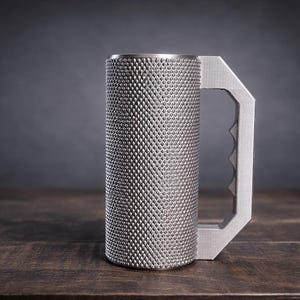 Peut inclure: Une tasse cylindrique en m&eacute;tal avec une surface textur&eacute;e &agrave; motif de losanges et une poign&eacute;e plate et angulaire comportant une s&eacute;rie de rainures pour les doigts sur le c&ocirc;t&eacute; int&eacute;rieur. La tasse est faite d'un mat&eacute;riau argent&eacute; mat.