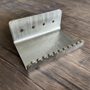 May include: A silver door handle opener with a serrated edge and the text "No Touching" and "USA Made".