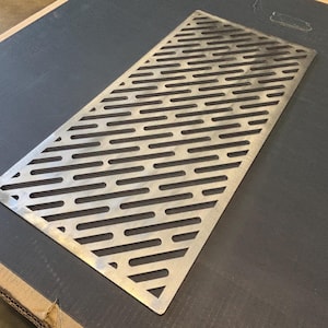 May include: A rectangular metal vent cover with a pattern of diagonal slots. The cover is silver and lies on a dark surface. The design is suitable for various applications, offering both functionality and a modern aesthetic.