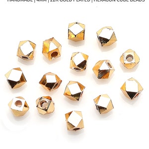 May include: A lot of 5 gold-plated hexagon cube charm beads, each measuring 4 mm. The beads are handmade and have a shiny finish.