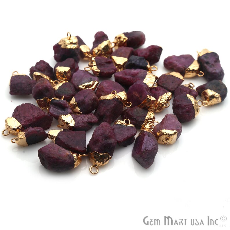May include: A collection of raw ruby gemstone pendants with gold accents. Each pendant has a gold bail for easy attachment to jewelry making projects.