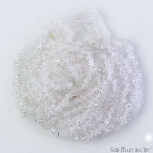 May include: A strand of clear quartz crystal chips. The chips are small and irregular in shape, and they are arranged in a loose pile.