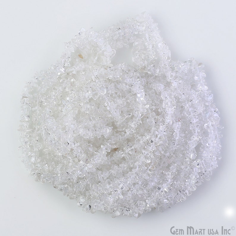 May include: A strand of clear quartz crystal chips. The chips are small and irregular in shape, and they are arranged in a loose pile.