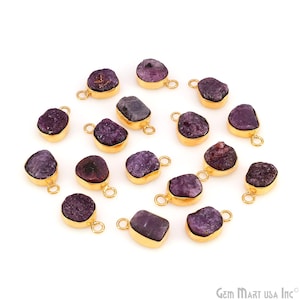 May include: A collection of raw, purple gemstone pendants with gold-colored metal settings. Each pendant has a unique, irregular shape and a small loop for attaching to a chain or other jewelry component. The gemstones vary in shade from light to dark purple.
