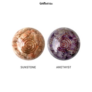 K&ouml;nnte beinhalten: Zwei runde, polierte Steine mit einem Kupferdraht-Spiralendesign. Der Stein links ist ein hellorangener Sunstone. Der Stein rechts ist ein violetter Amethyst. GemMart USA.