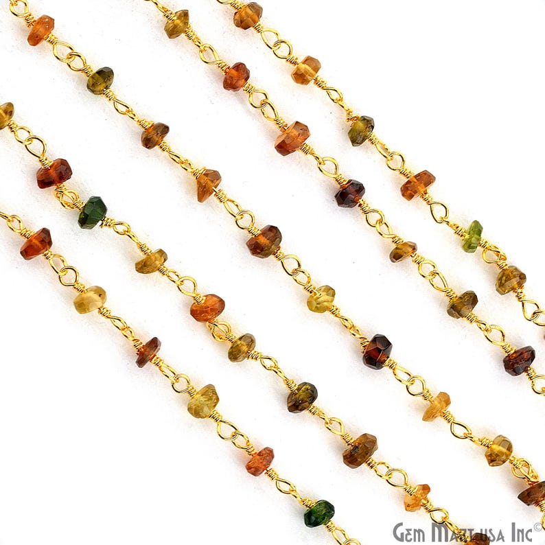 May include: A gold-toned metal chain featuring small, faceted, multi-coloured gemstone beads in shades of amber, brown, and green. The stones are individually wire-wrapped and spaced evenly along the delicate links of the metallic chain.