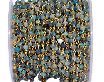 May include: A spool of turquoise and green gemstone beads strung on a gold chain. The chain is made of small, linked rings. The beads are irregular in shape and have a rough, natural texture.