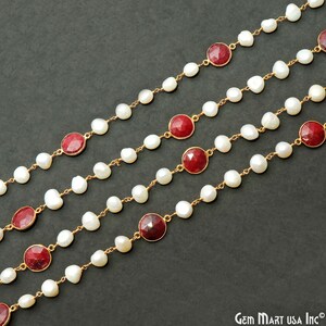 Può includere: Quattro fili di una collana con perle bianche e accenti di pietre preziose rosse. La collana è realizzata con una catena d'oro.