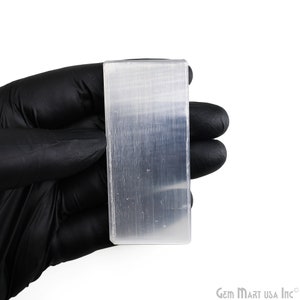 May include: A clear selenite crystal slab with a smooth, polished surface. The crystal is rectangular in shape and has a slightly cloudy appearance.