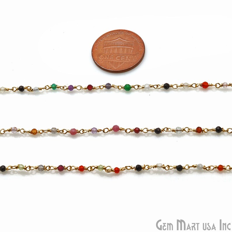 May include: Three strands of gold chain with various colored beads, including red, green, black, and clear. The chain is shown next to a US penny for scale.