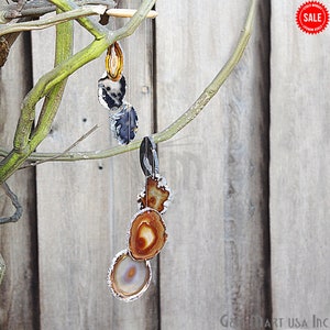 May include: A hanging mobile featuring several agate slices in shades of brown, orange, gray, and white, with silver-colored edges. The agate slices are suspended from a wooden branch with thin strings, creating a natural and decorative element.